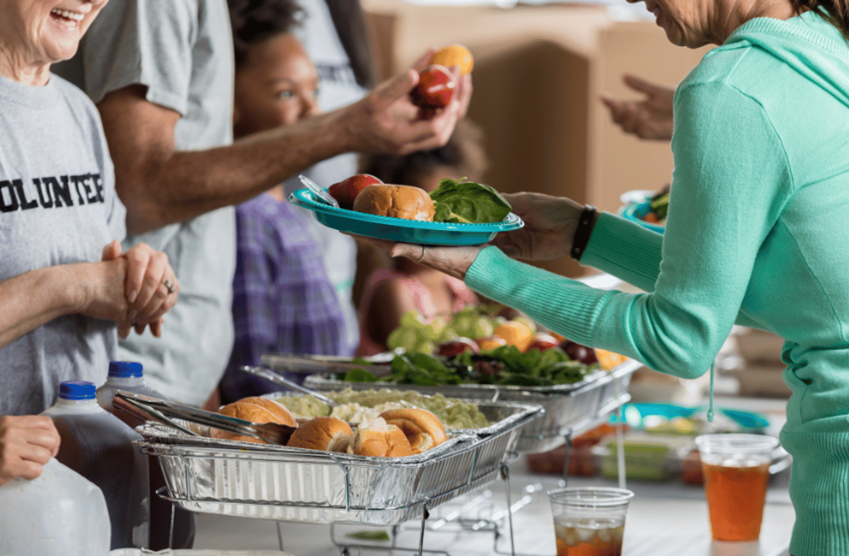 Volunteers hand plates of food across the serving line