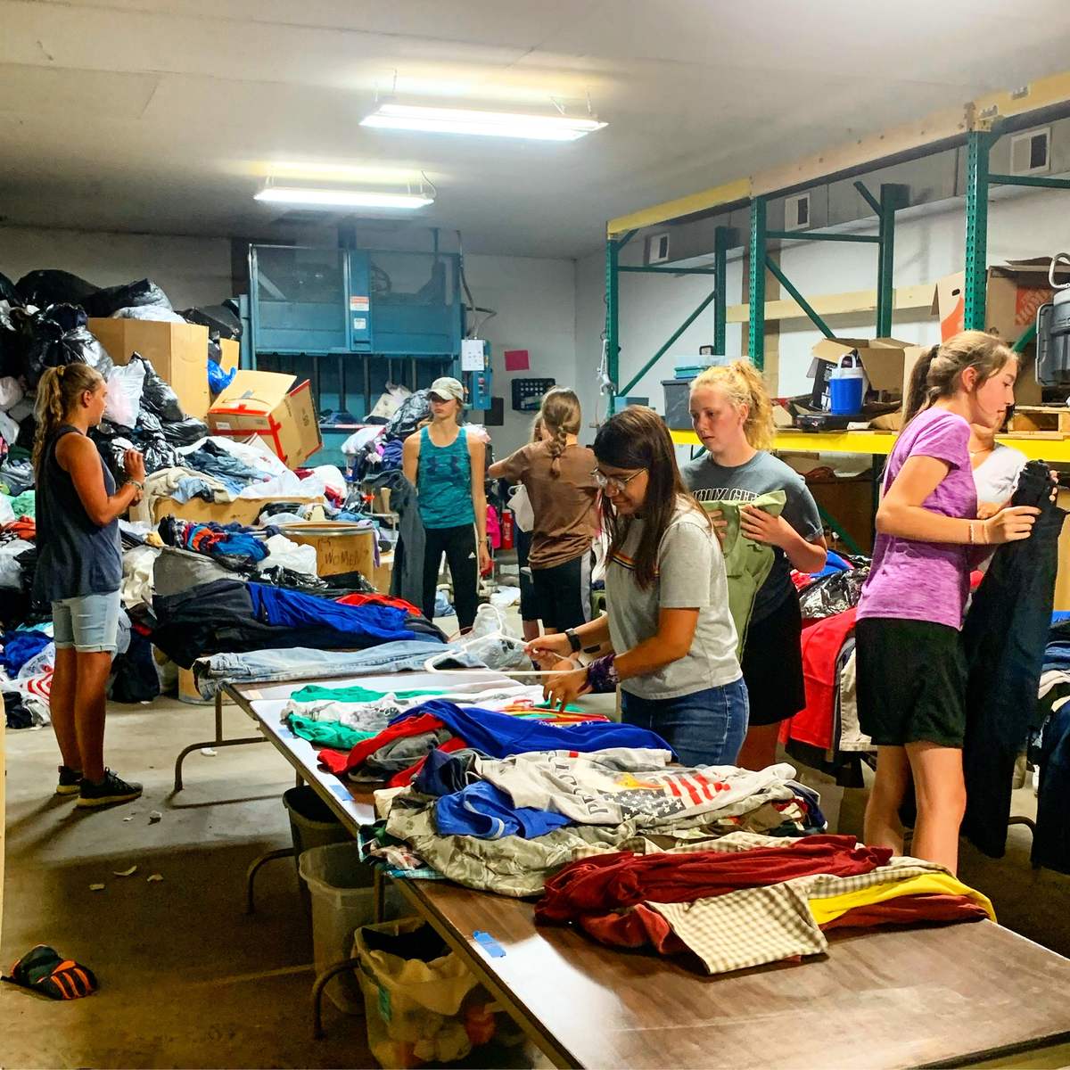 Volunteers sorting donated clothing at long tables